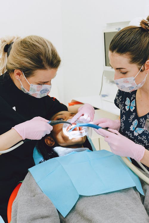 Female dentist with assistant treating patient in clinic
