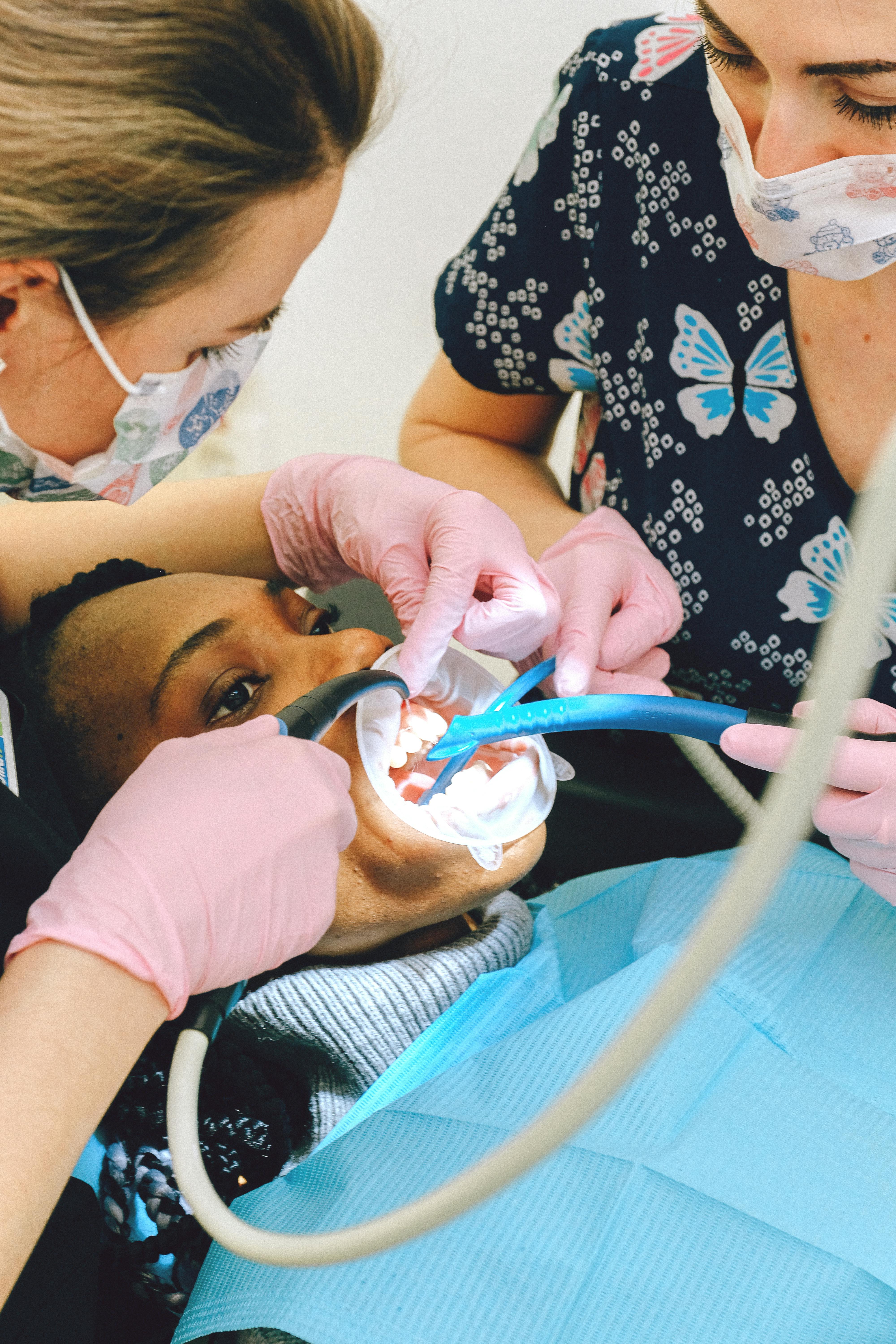 female dentists treating teeth of client in modern clinic