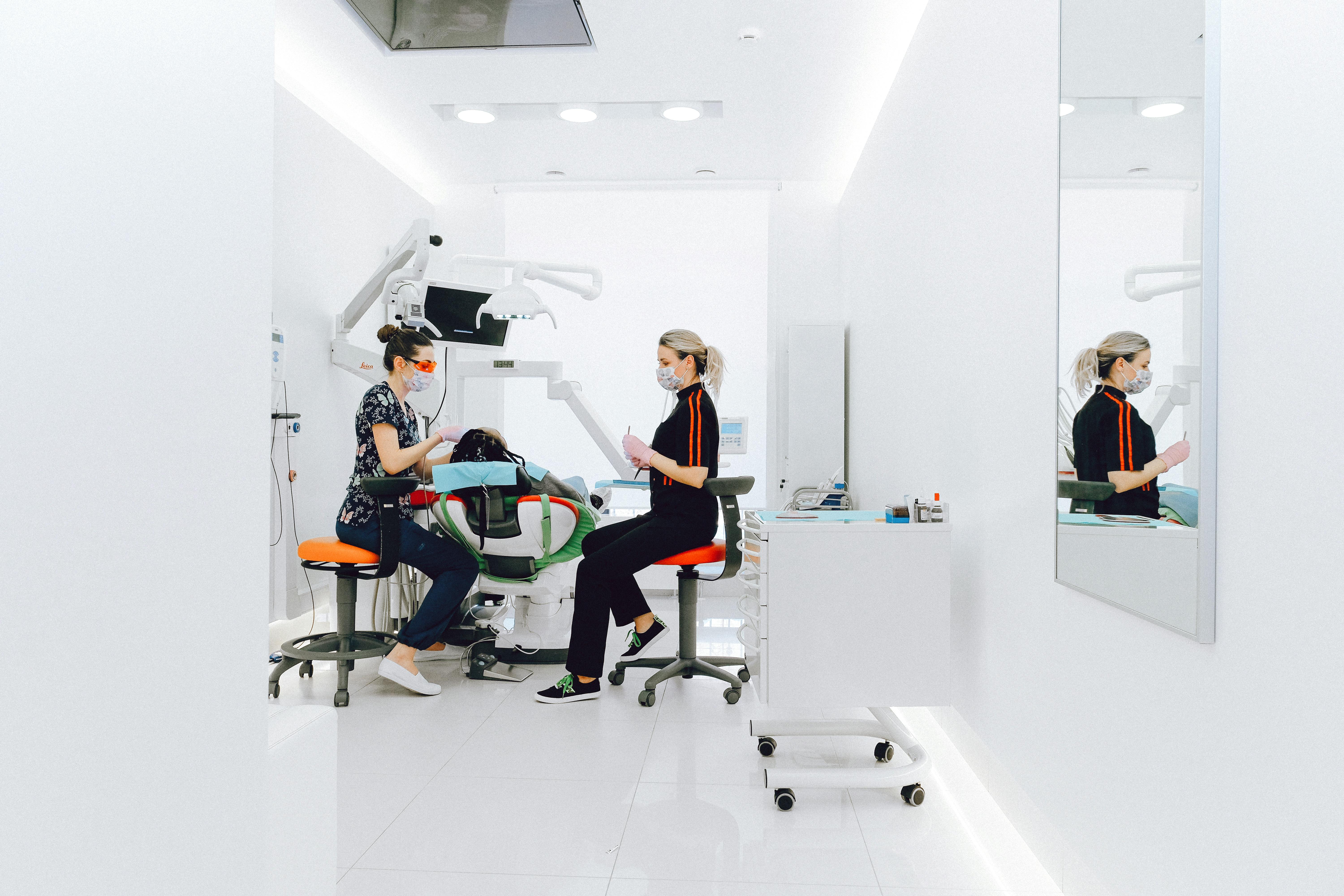 female dentist and assistant examining patients teeth in clinic