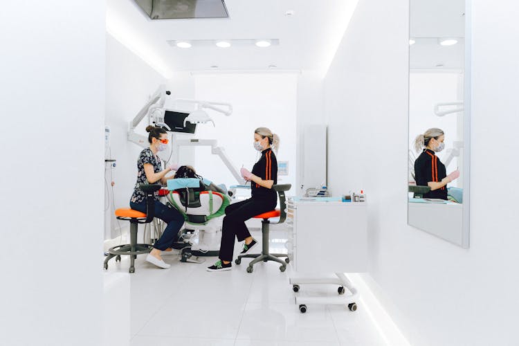 Female Dentist And Assistant Examining Patients Teeth In Clinic