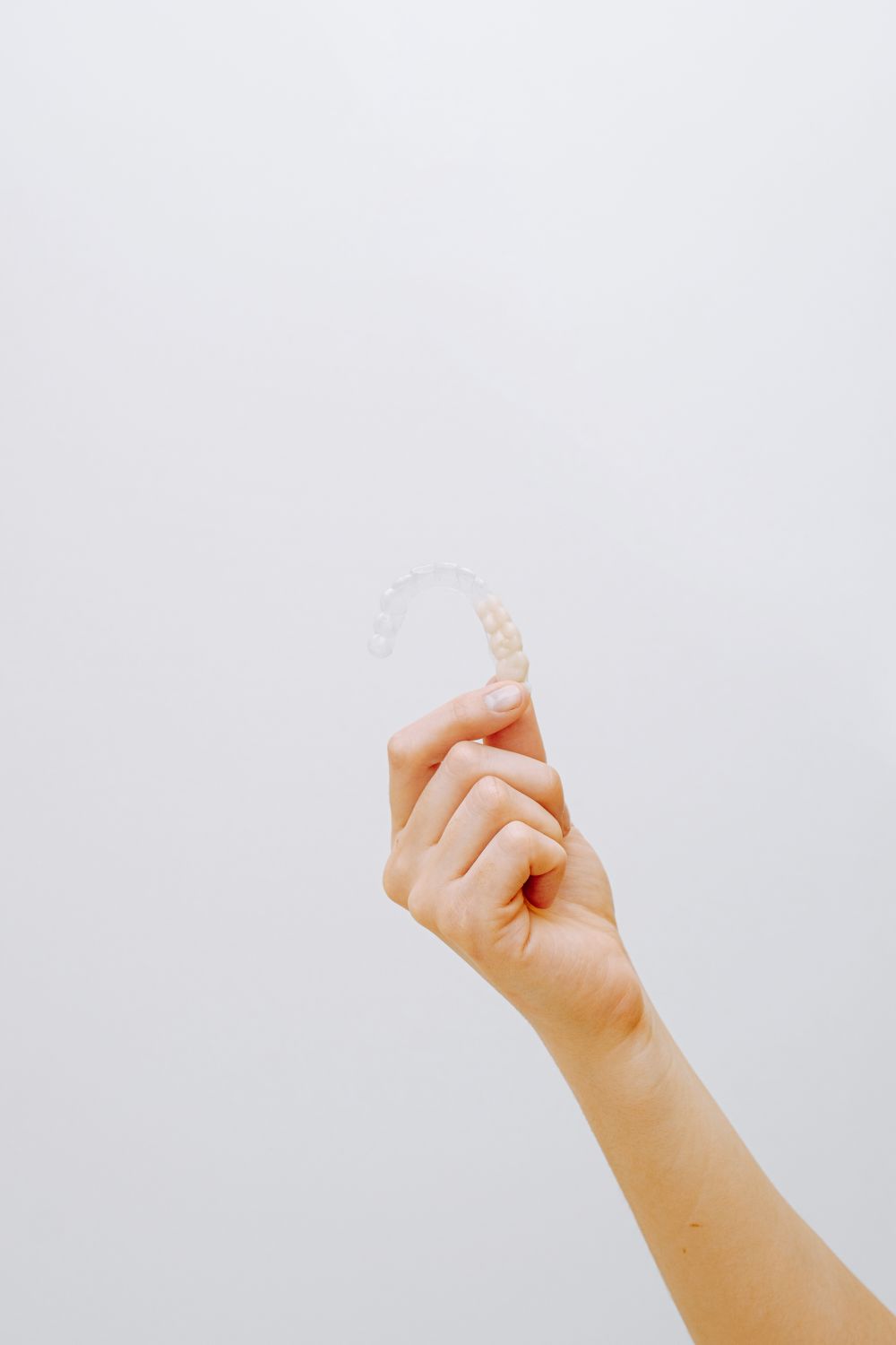 A hand holding a clear dental aligner