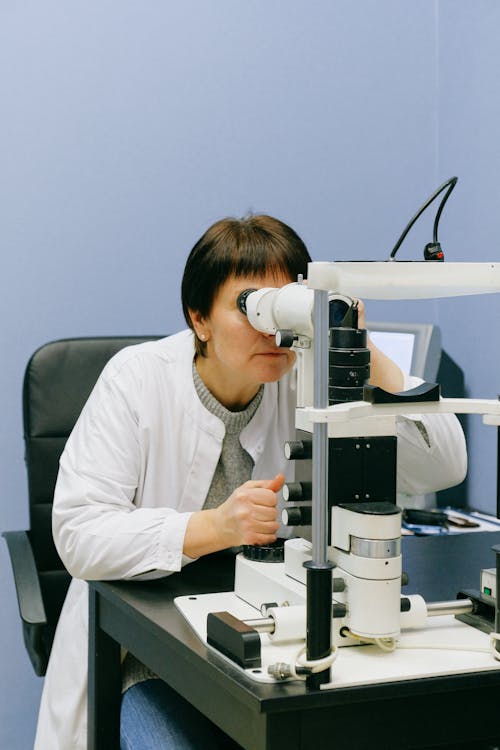 Gratis Investigadora Anónima Mirando A Través Del Microscopio De Lámpara De Hendidura Foto de stock