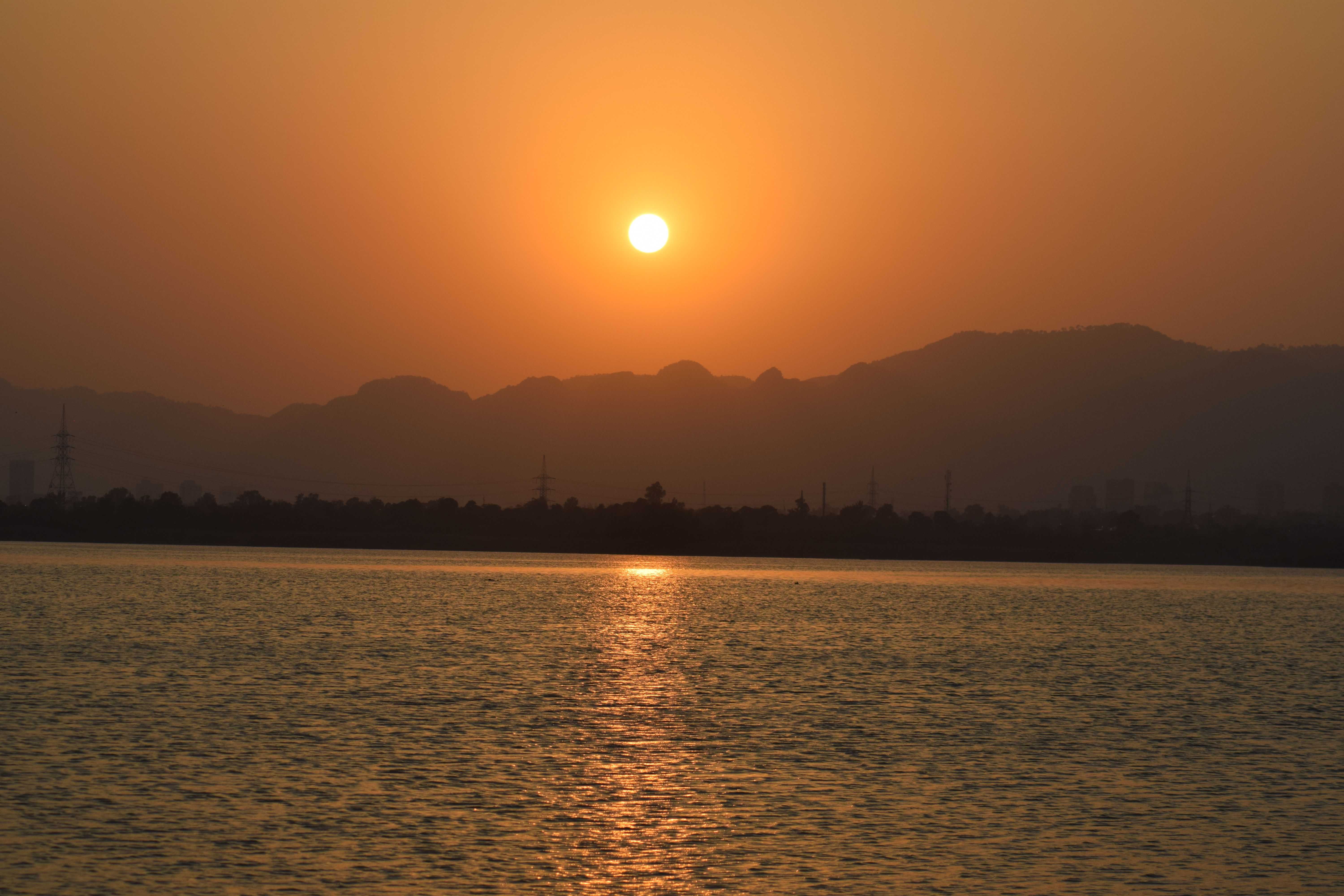 Scenic sunset over the serene waters and mountains in Islamabad, Pakistan.