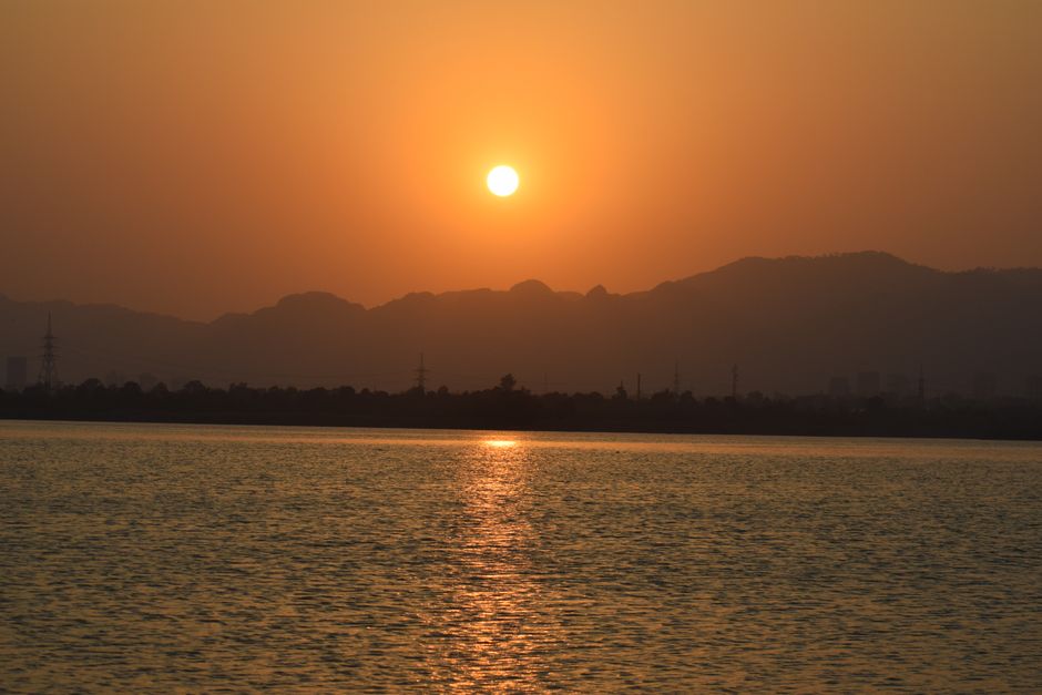 Scenic sunset over the serene waters and mountains in Islamabad, Pakistan.