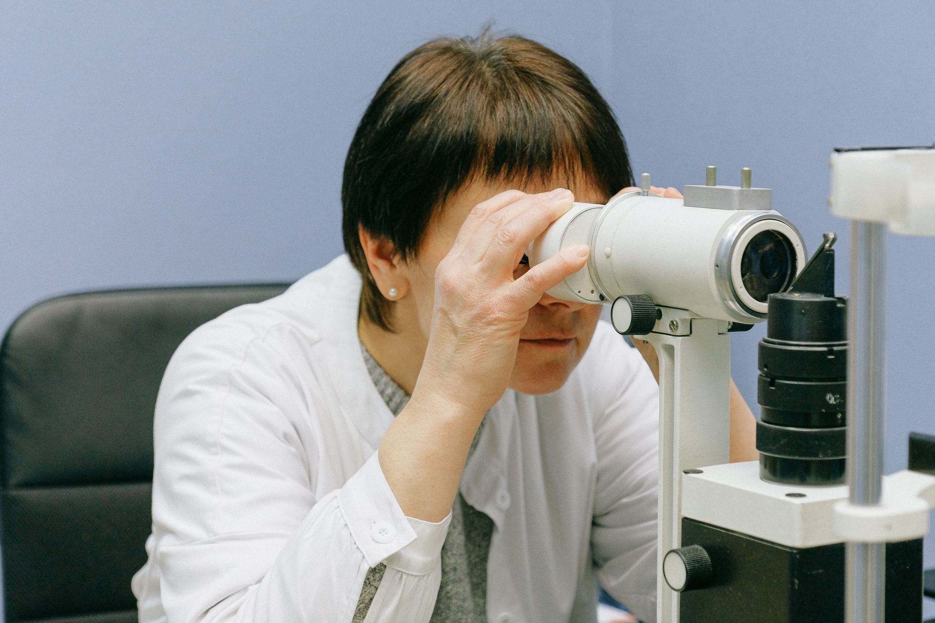 Woman focused on scientific research using a laboratory microscope indoors.