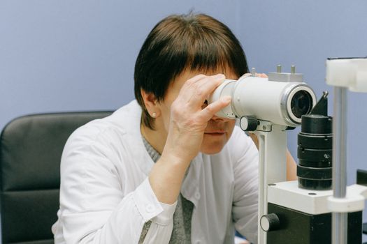 一名妇女在室内专注地使用实验室显微镜进行科学研究