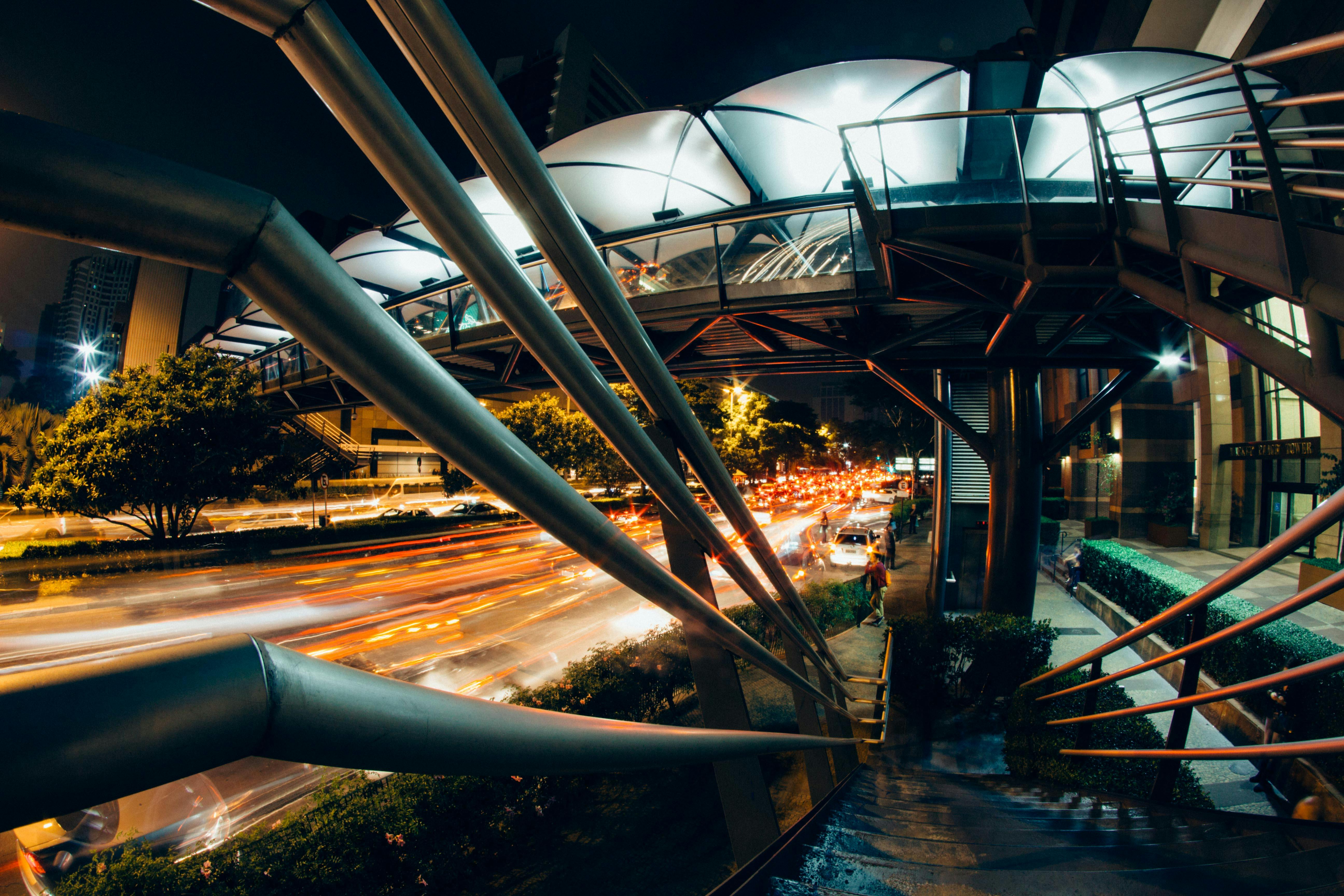 夜幕下，城市景观充满活力，一座现代化的桥梁横跨下方，交通繁忙