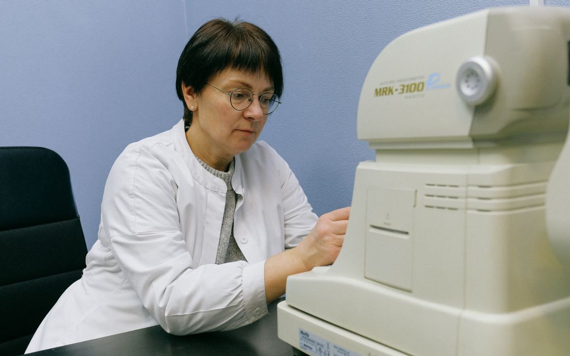 Eye doctor using an automatic refractometer-keratometer to take eye measurements in a clinic office