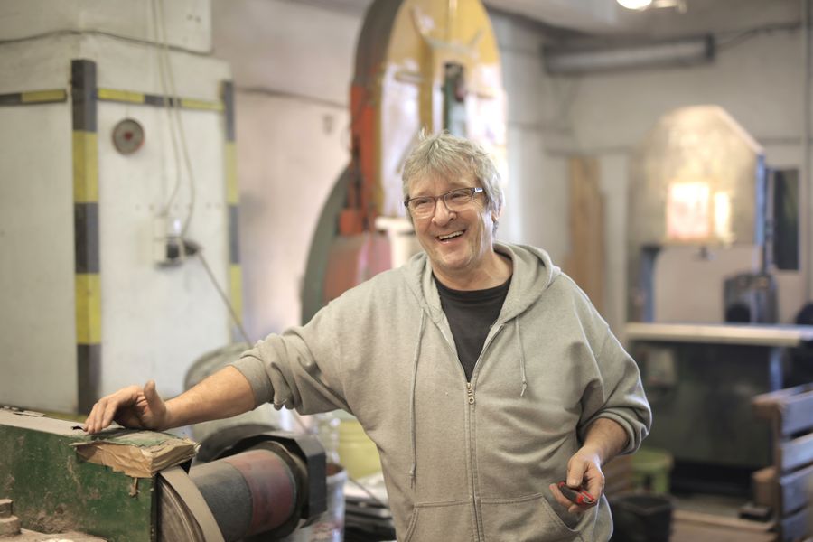Erik Halverson, master carpenter, smiling in his workshop surrounded by hardwood pieces