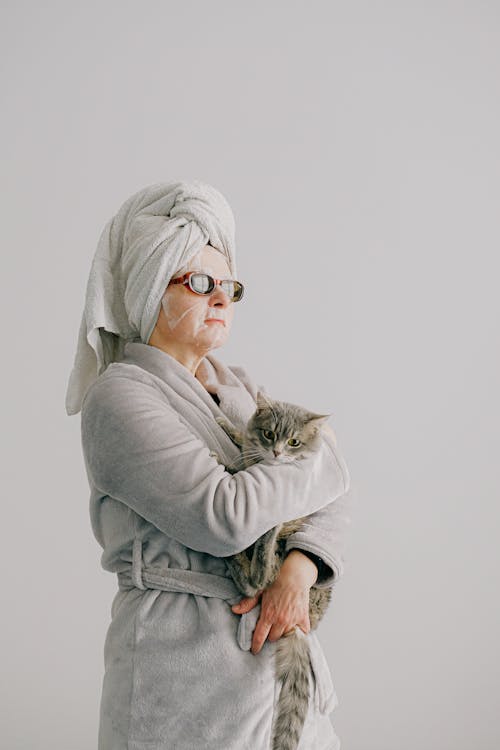 Woman after bath standing with cat in arms