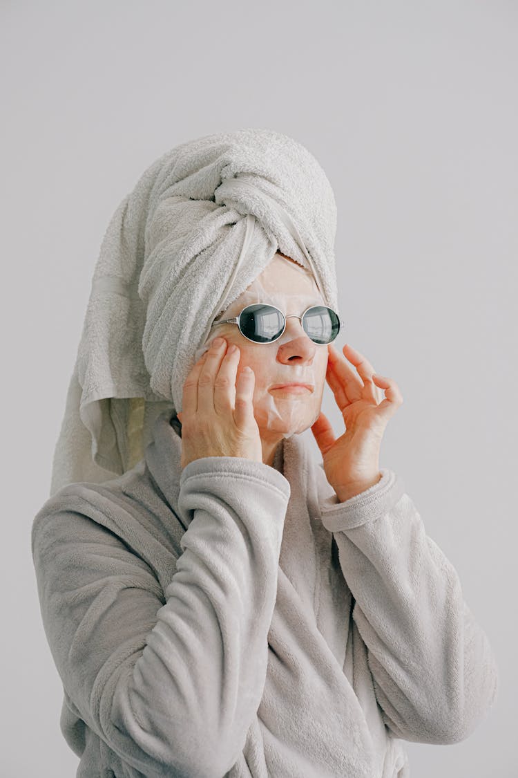 Senior Female Touching Face With White Sheet Mask