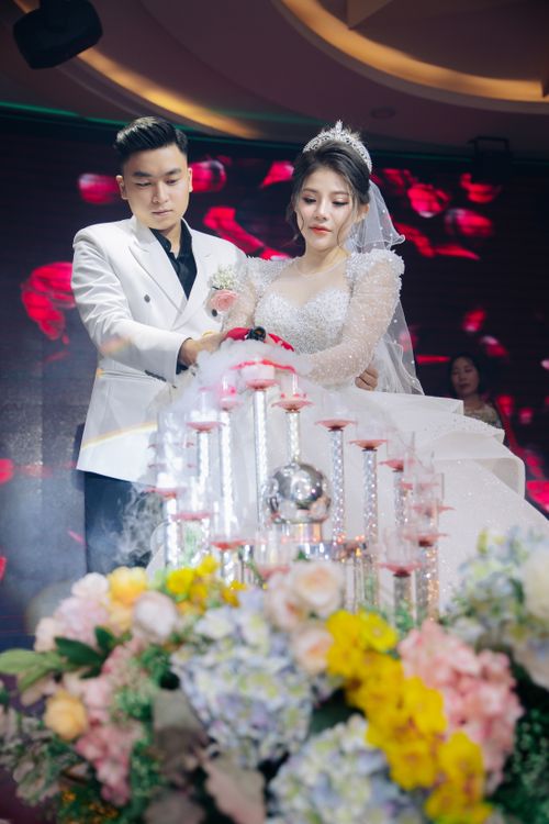 Free Bride and groom at a wedding cutting a cake adorned with flowers and elegant candles. Stock Photo
