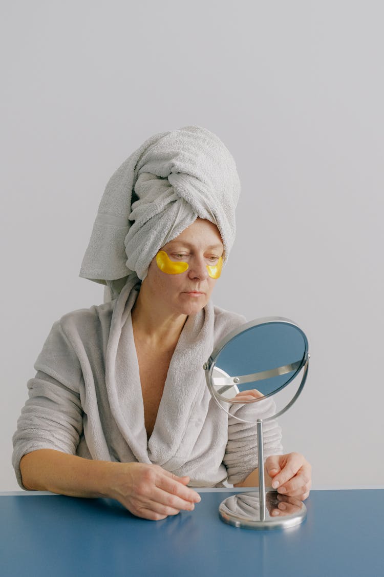 Serious Female In Eye Patches Looking In Mirror