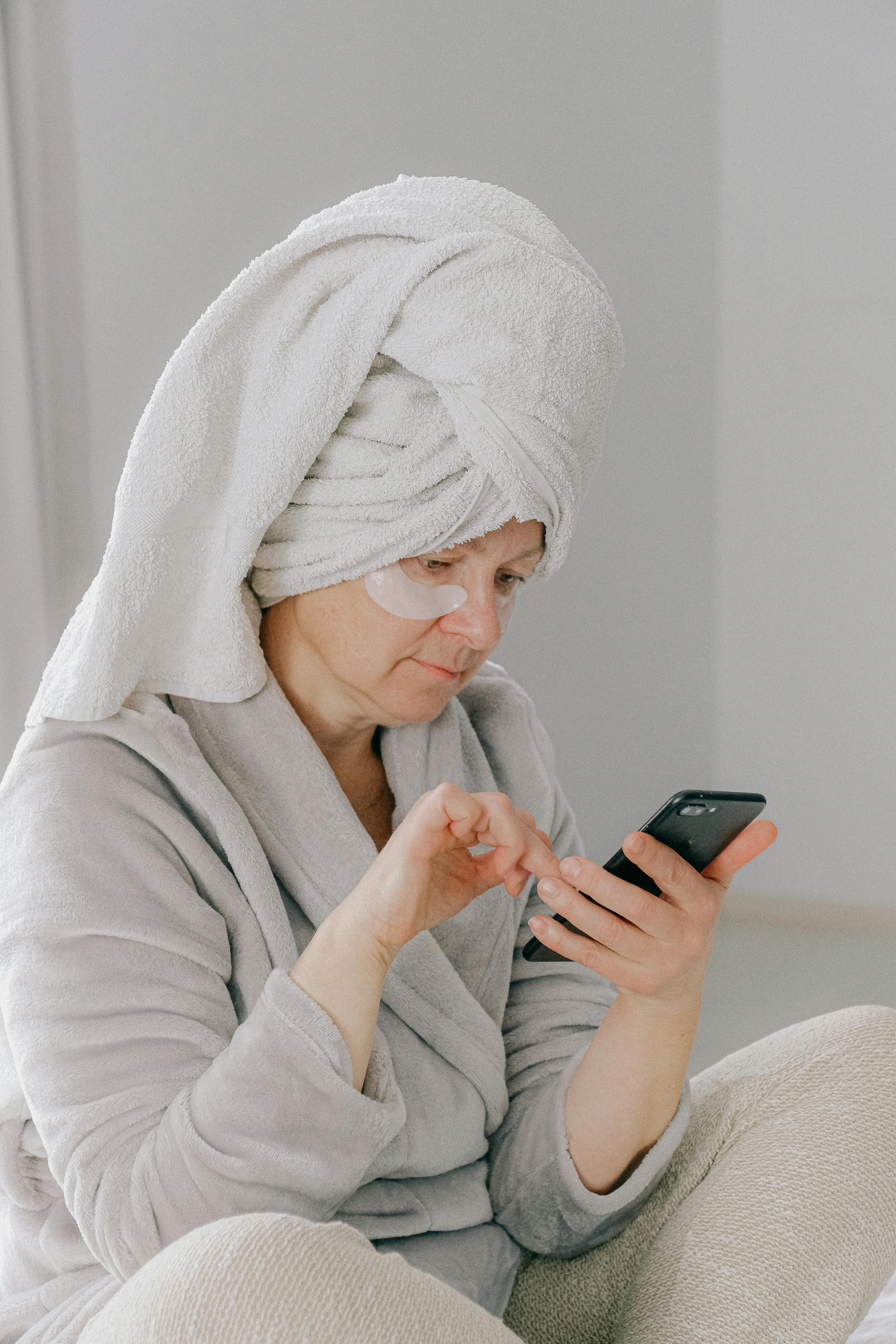 一位穿着浴袍的妇女在室内放松时使用智能手机，象征着舒适与科技的结合