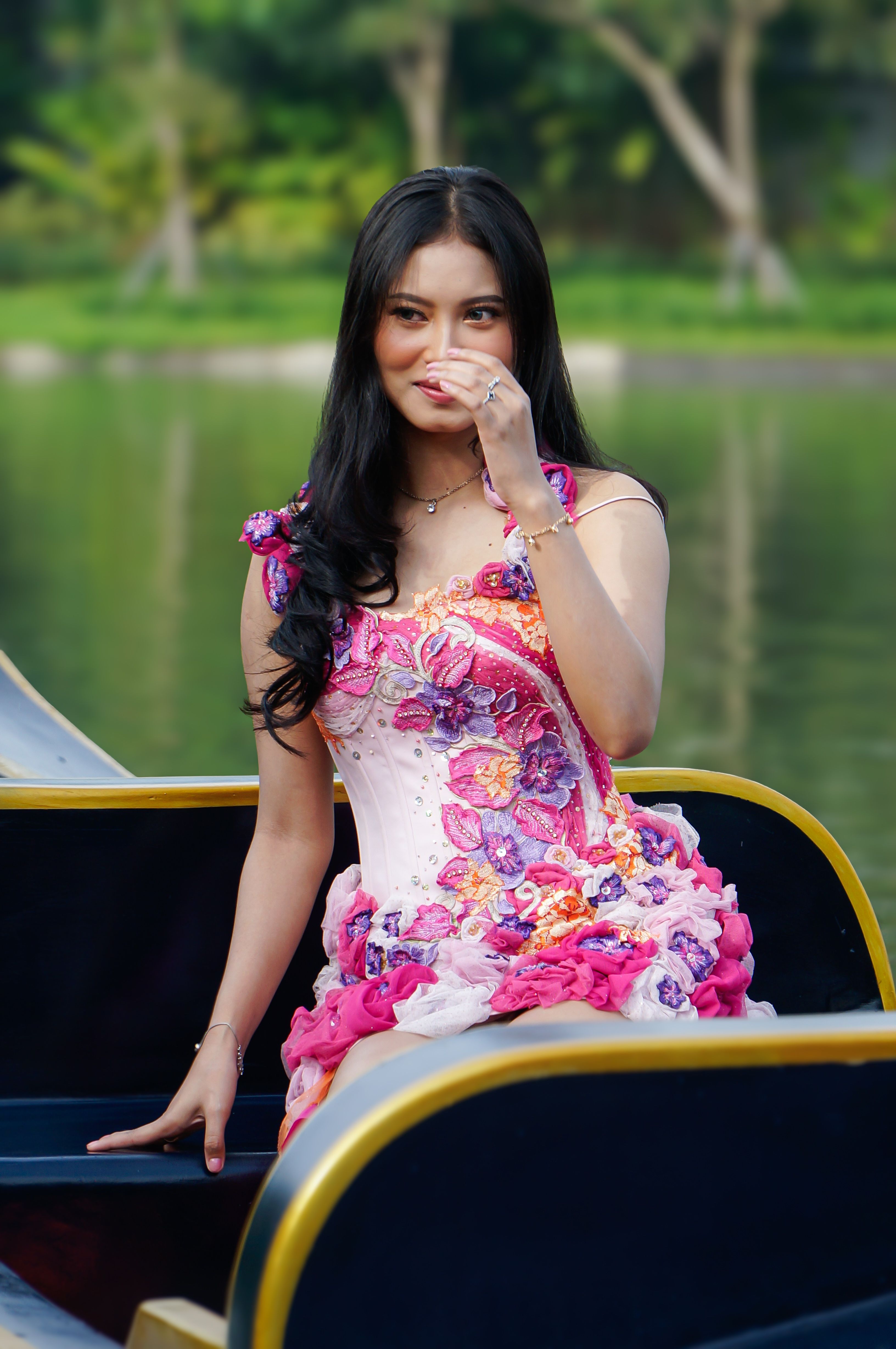 A woman in a vibrant floral dress enjoying a day outdoors on a canoe, surrounded by nature.