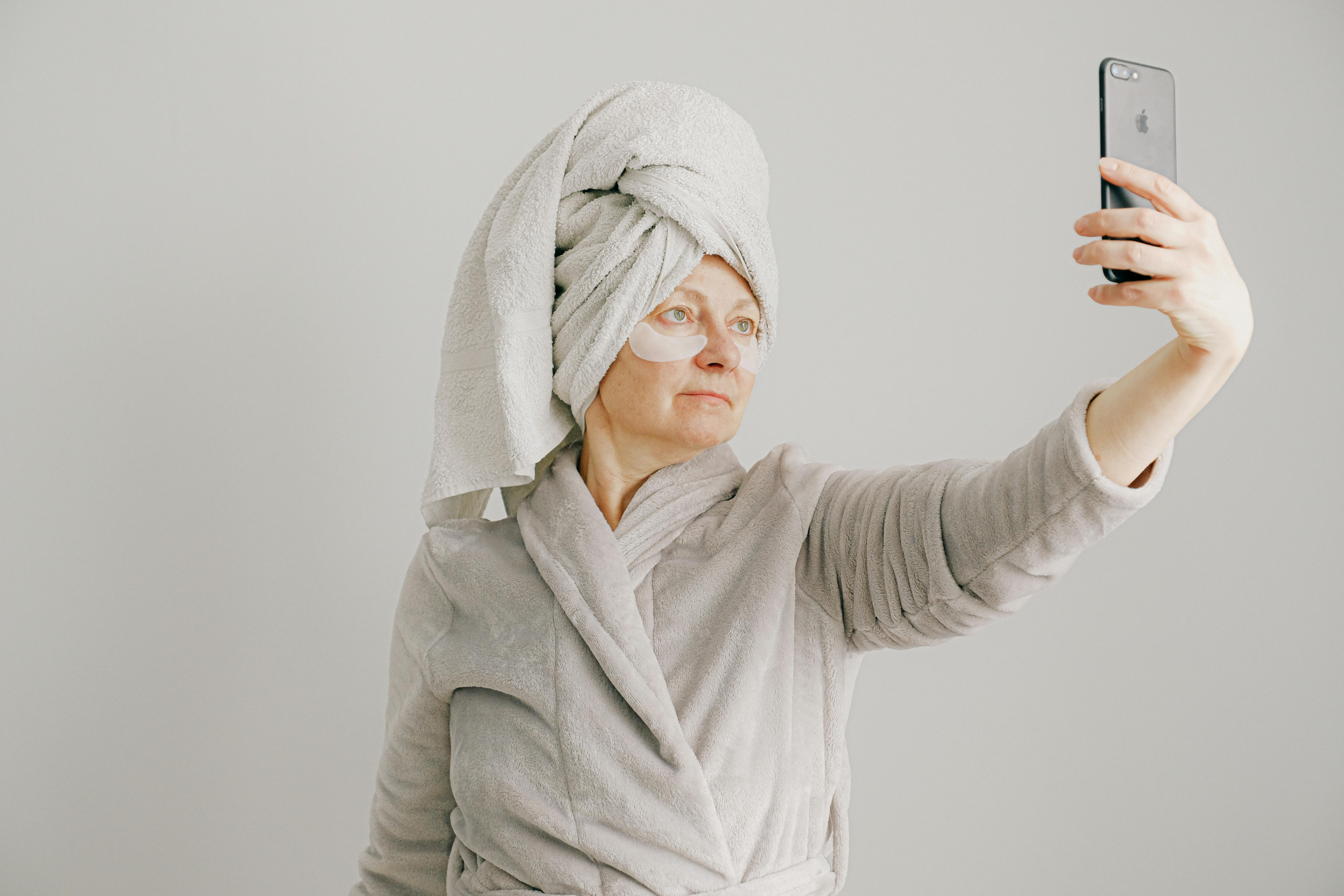 A woman in gray bathrobe holding a mobile phone. | Photo: Pexels