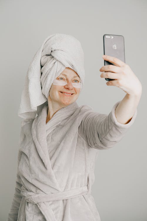拿着i Phone的灰色浴袍的女人