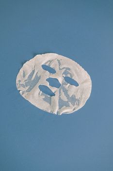 白色片状面膜在鲜艳的蓝色表面上，非常适合护肤和美容概念