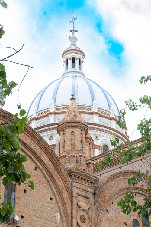 Free Iconic blue domes of the Cathedral of the Immaculate Conception in Cuenca, Ecuador, framed by lush greenery. Stock Photo