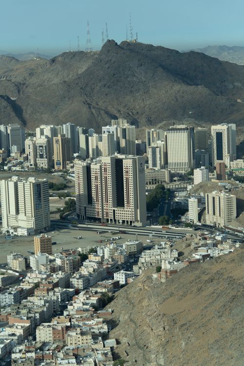 Free A dramatic aerial view capturing the skyline of Makkah, Saudi Arabia, with surrounding mountains, showcasing urban life and architecture. Stock Photo