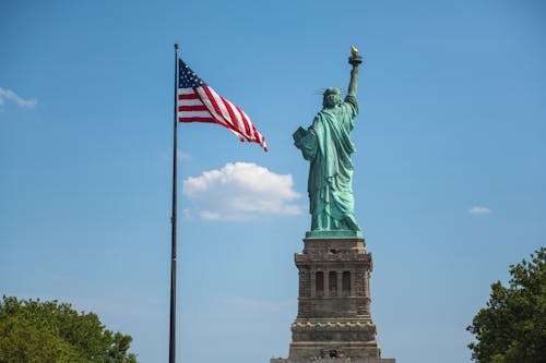 Free Flag of America near the Statue of Liberty Stock Photo