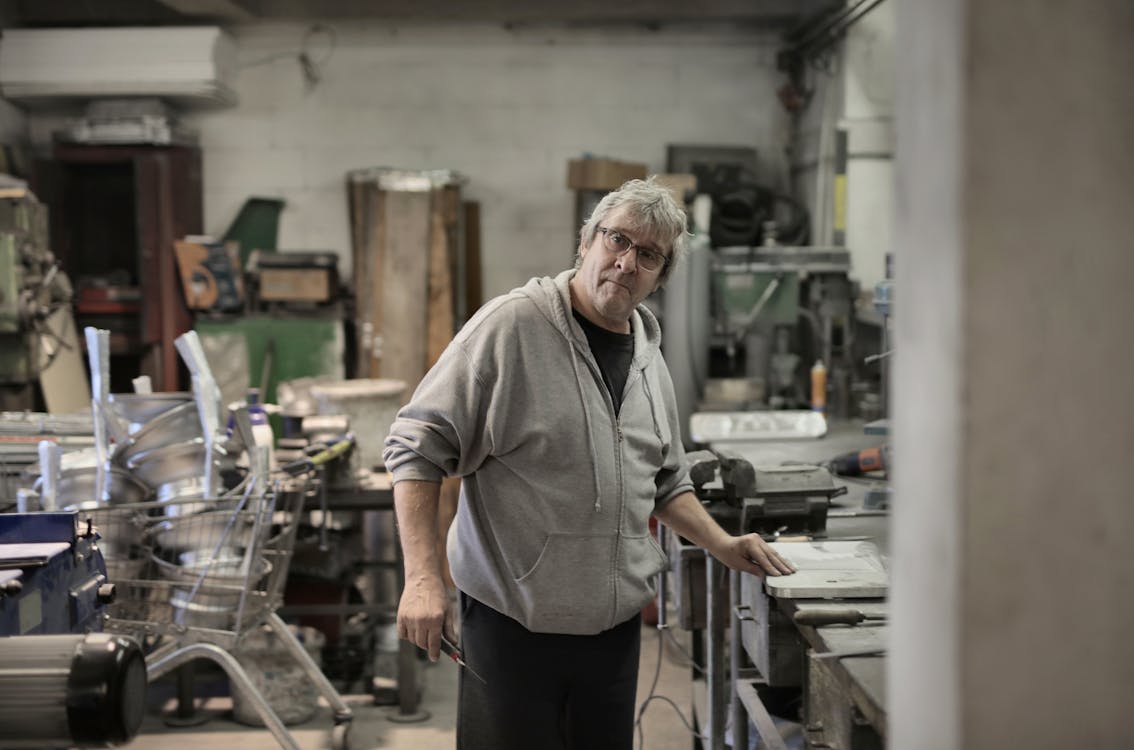 Lavoratore Invecchiato Capelli Bianchi In Piedi Vicino Al Banco Di Lavoro