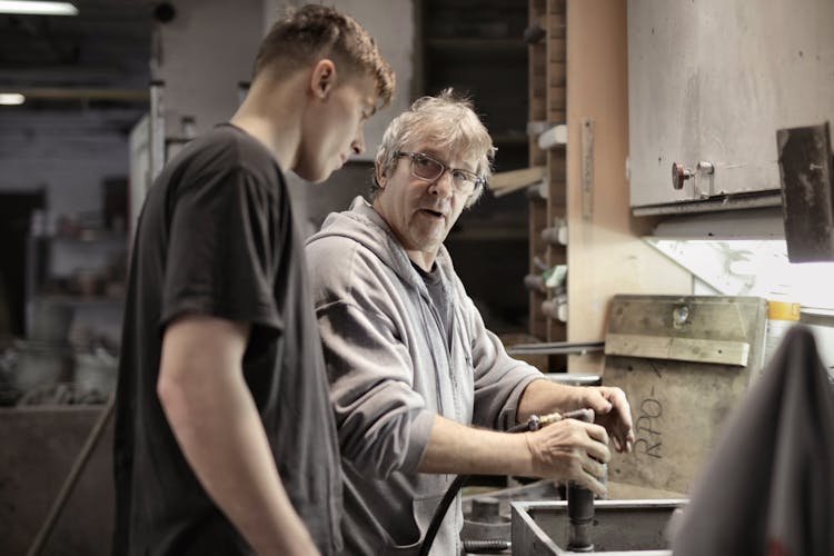 Workers Handling Detail By Pneumatic Tool In Workshop