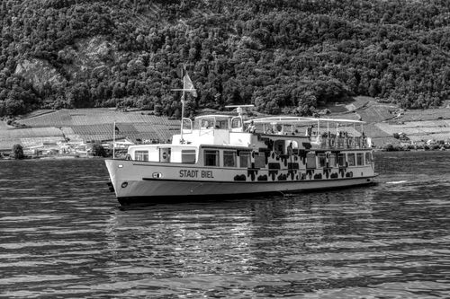Free Scenic view of Stadt Biel ferry cruising a Swiss lake with mountainous backdrop in monochrome. Stock Photo