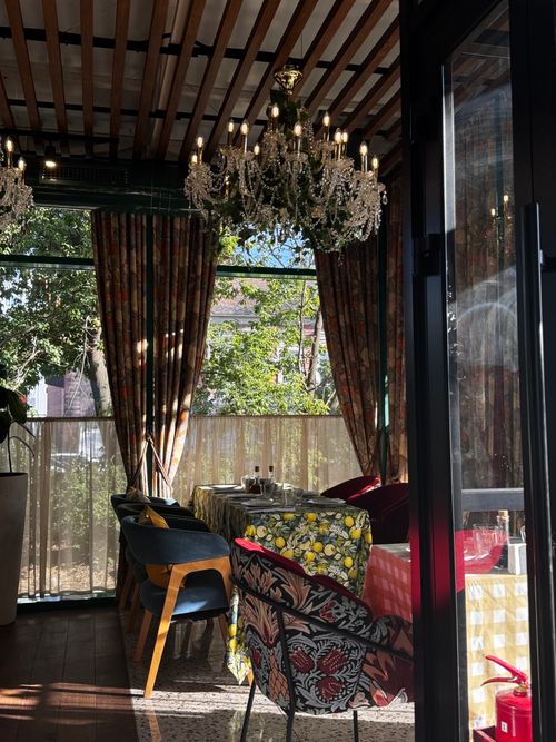 Free Cozy restaurant dining area with ornate chandeliers and eclectic decor in a sunny, rustic setting. Stock Photo