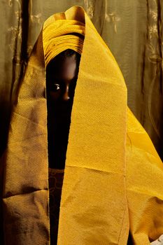 Artistic portrait of a woman partially hidden behind bright yellow cloth, creating a mysterious ambiance.