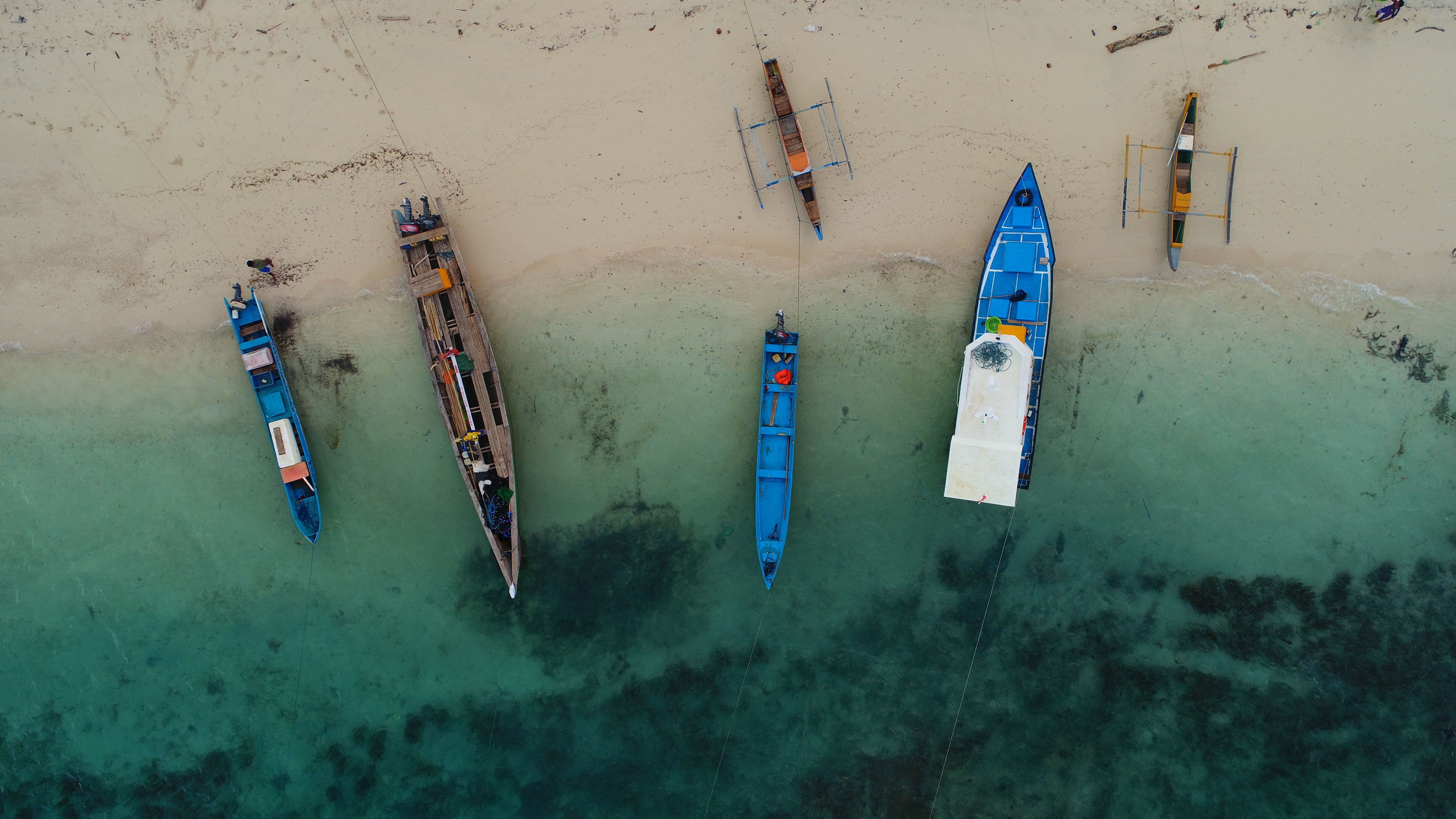 Aerial shot of traditional boats on the sandy shore of a tropical beach in North Maluku, Indonesia.