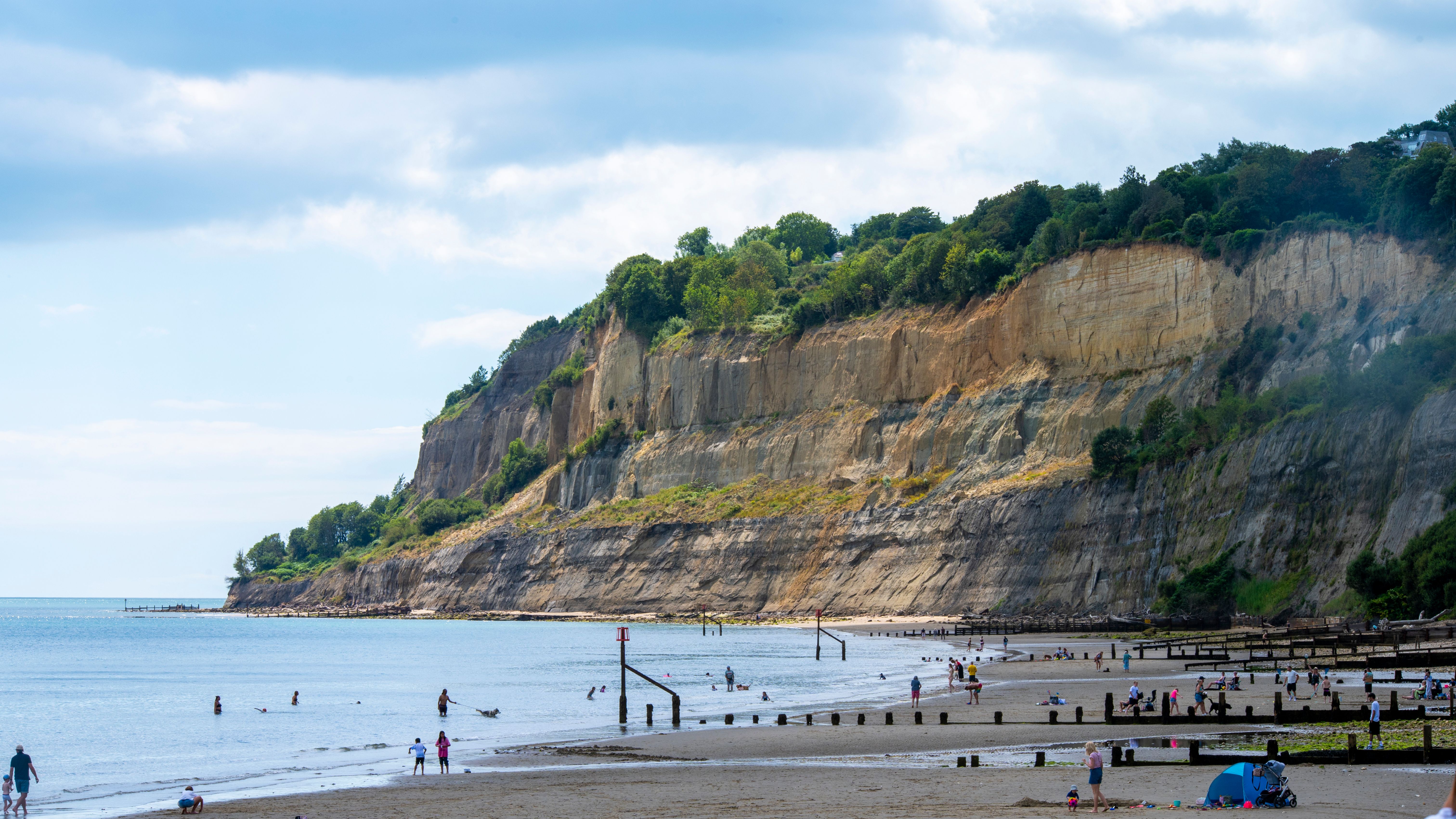 Beautiful seaside cliff beach scene with people enjoying a summer day.