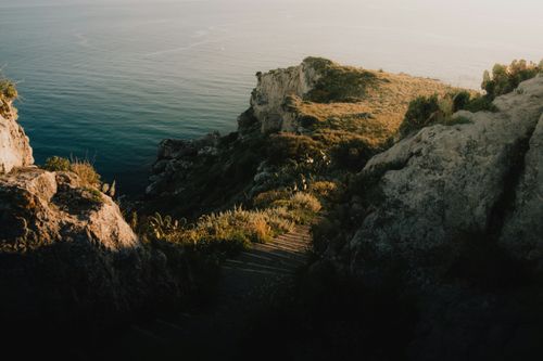 Free Tranquil view of a rocky coastal path with sunset over the sea in Italy. Stock Photo