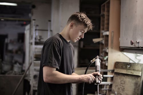 Jeune Mécanicien Travaillant Attentivement En Atelier