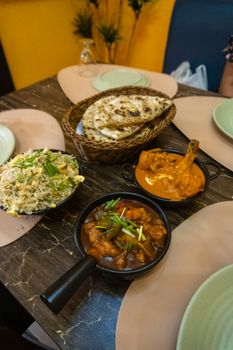 Delectable Indian curry dishes served with naan bread on a wooden table, perfect for a hearty meal.