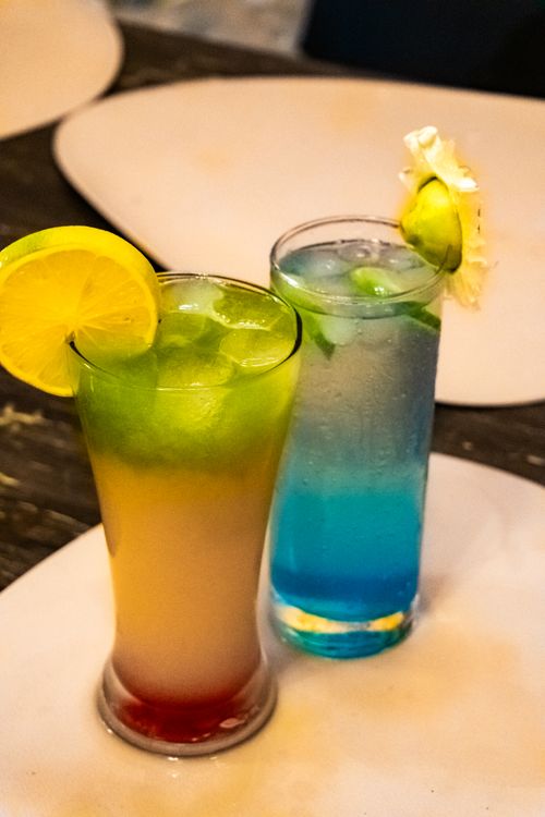 Free Colorful tropical cocktails with lemon and lime garnishes on a table. Stock Photo