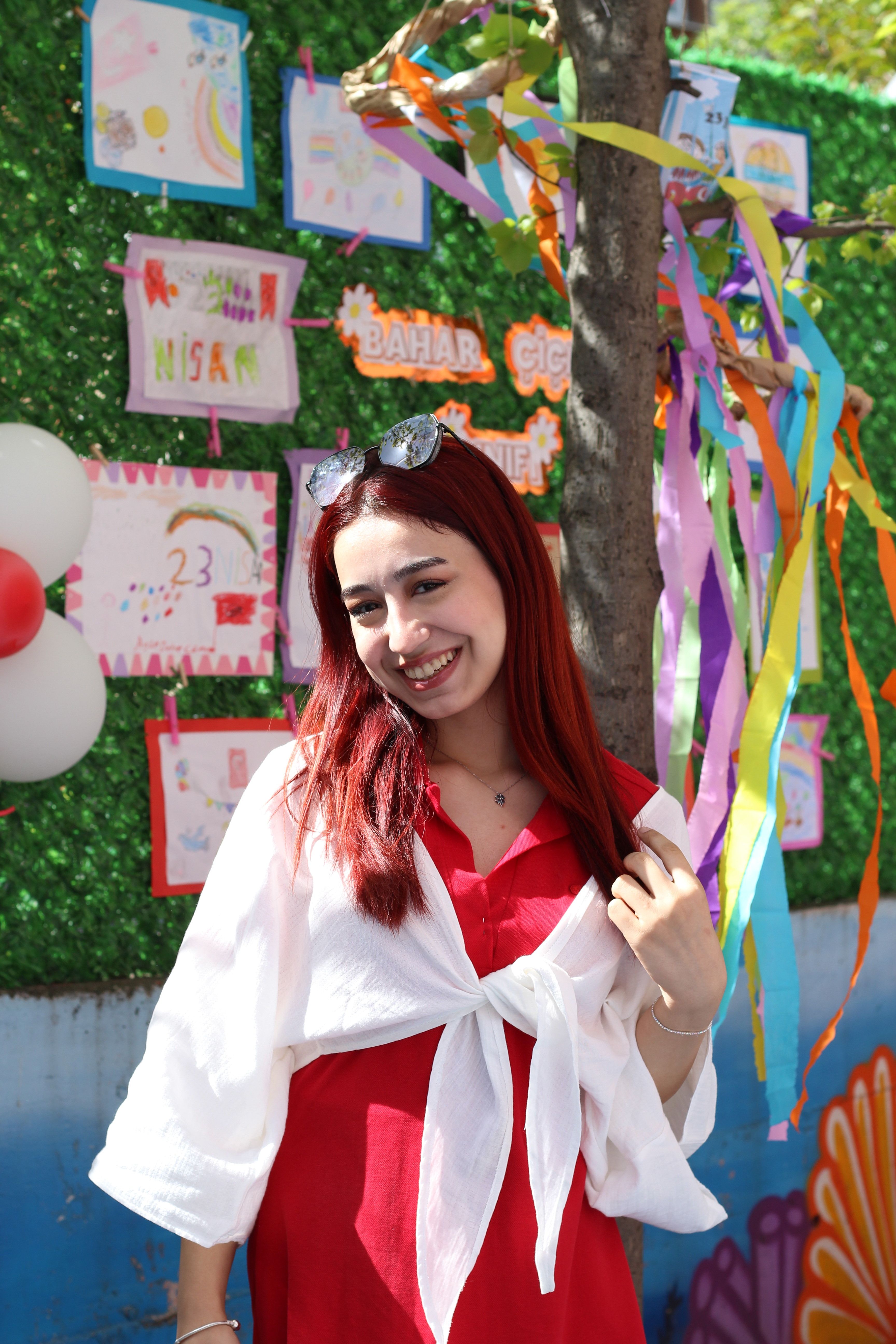Smiling young woman enjoying an outdoor celebration with colorful decorations and joyful atmosphere.