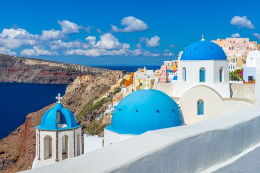 Capture the breathtaking scenery of Santorini's unique architecture and vibrant blue domes under a clear summer sky.