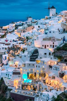 Charming evening view of Santorini's distinctive white buildings and windmills.