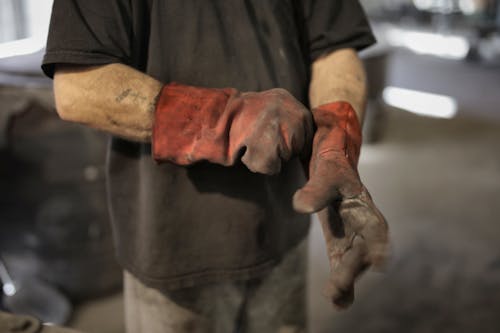 Free From above of crop male fitter in shabby heavy duty gloves in workshop Stock Photo