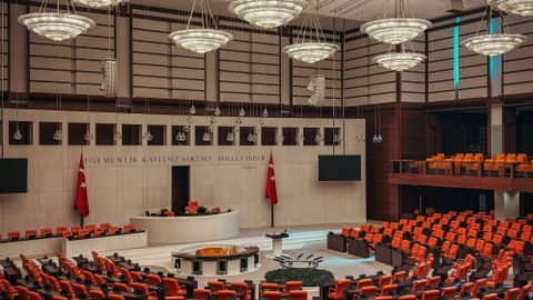 Spacious parliamentary hall with bold design, red seating, and elegant chandeliers.