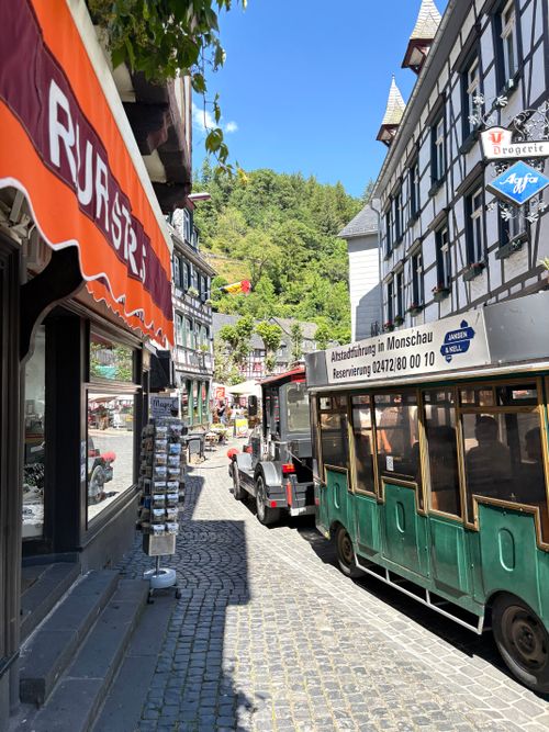 Free Sunny day on a quaint Monschau street featuring historical architecture and a tour bus. Stock Photo
