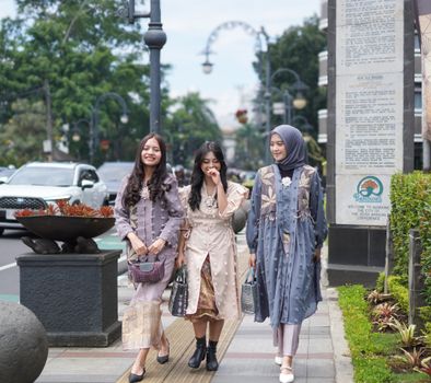 Three stylish women walk along a city street in Bandung, showcasing modern Indonesian fashion. - Fotografer Sidoarjo