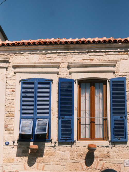 Free A picturesque stone building with blue shutters under a clear sky in İzmir, Türkiye. Stock Photo