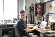 年轻人在充满工具的创意工作空间里微笑着使用笔记本电脑