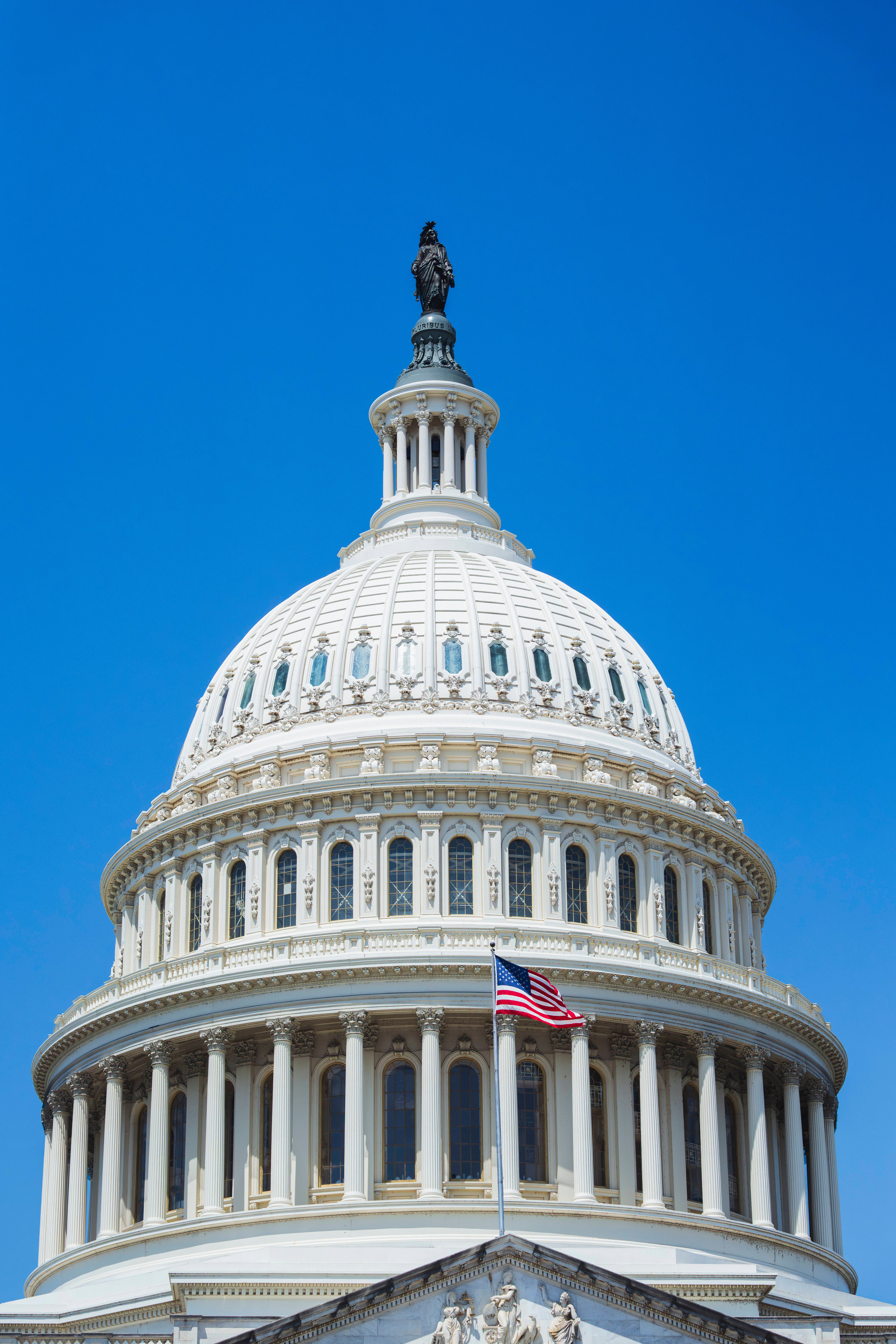 Close-up van de iconische koepel van het Capitool in Washington D.C., onder een helderblauwe hemel.