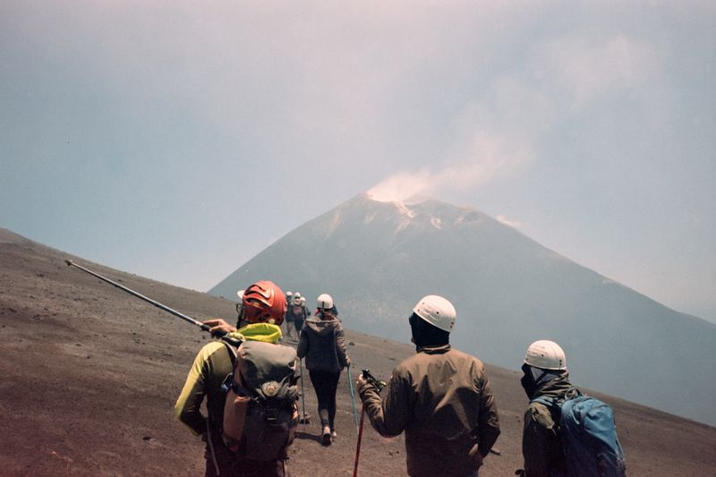 Adventurous hikers climbing volcanic Mount Etna on a clear day in Sicily, Italy.