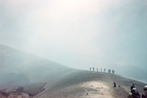 Free Group of hikers exploring the volcanic terrain of Mount Etna under a misty sky. Stock Photo