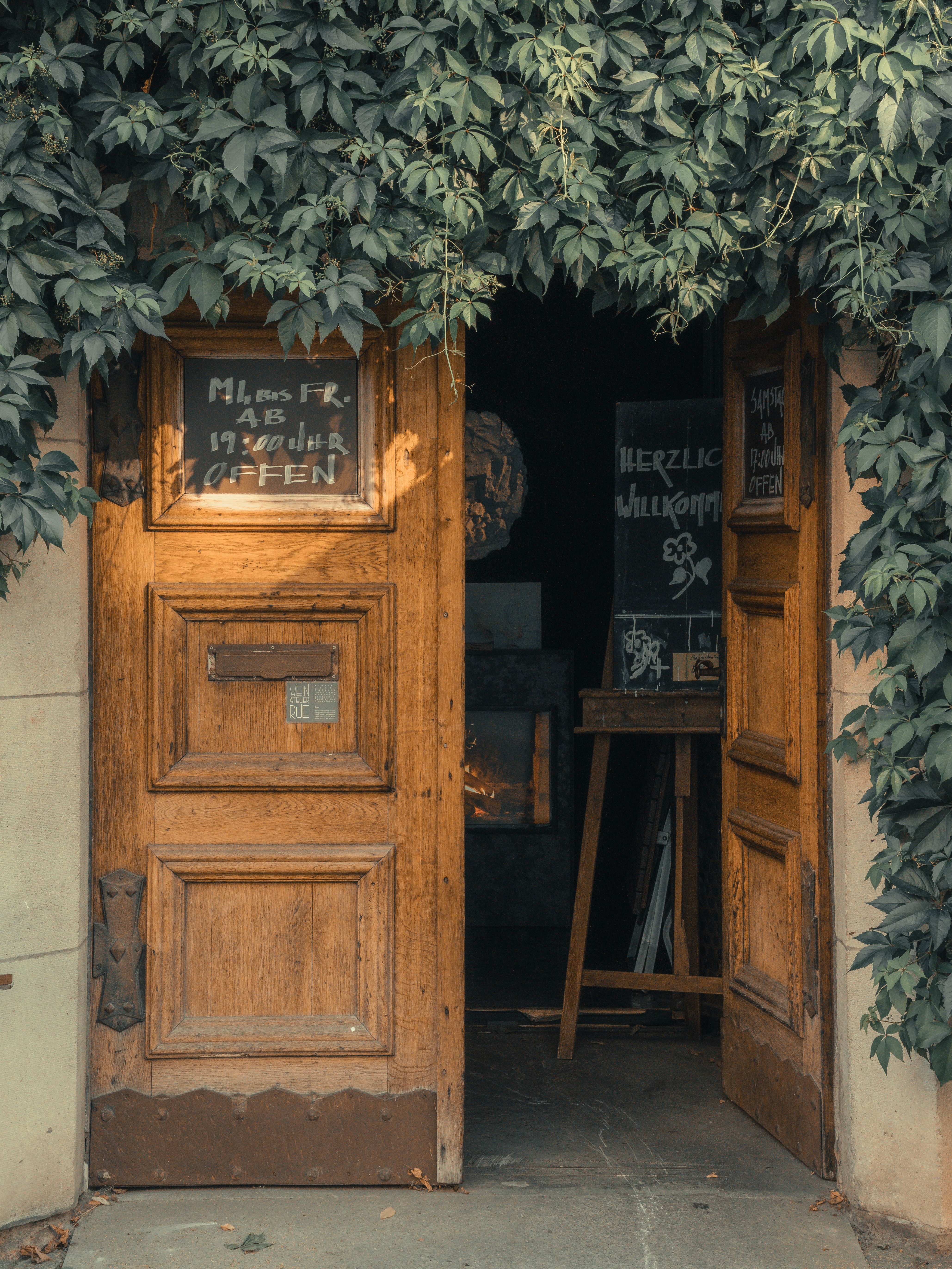 A warmly lit wooden door inviting visitors into a rustic European café.