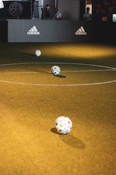 Three soccer balls on an indoor futsal court under warm lighting in Toronto, Canada.